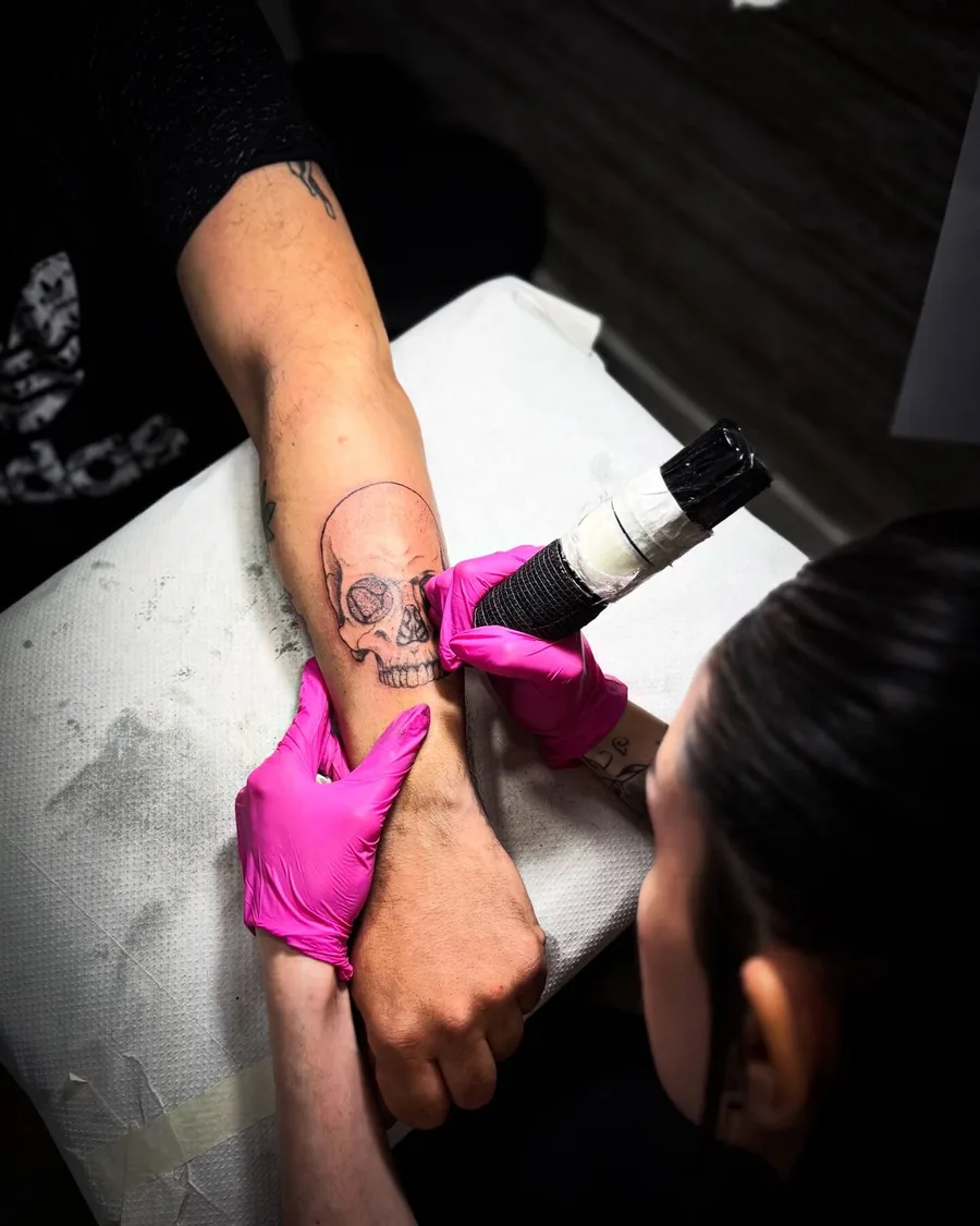Alumna tatuando una calavera en un brazo durante las prácticas de la escuela ESAP de Madrid