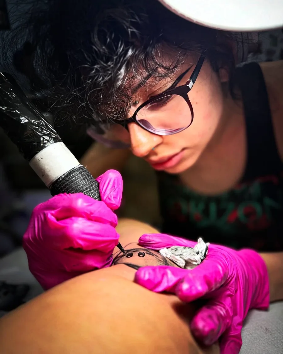 Alumna con gafas de protección tatuando una pierna en la escuela ESAP de Madrid Alumna con gafas de protección tatuando una pierna en la escuela ESAP de Madrid