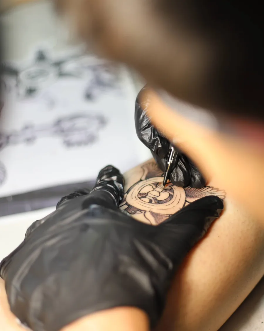 Alumno tatuando un diseño con guantes en la escuela ESAP de Madrid
