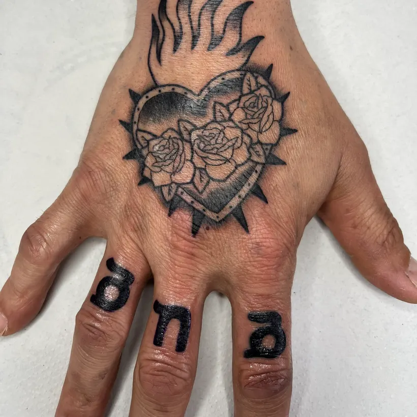 Tatuaje tradicional de sagrado corazón con rosas en el dorso de la mano, hecho en ESAP Madrid
